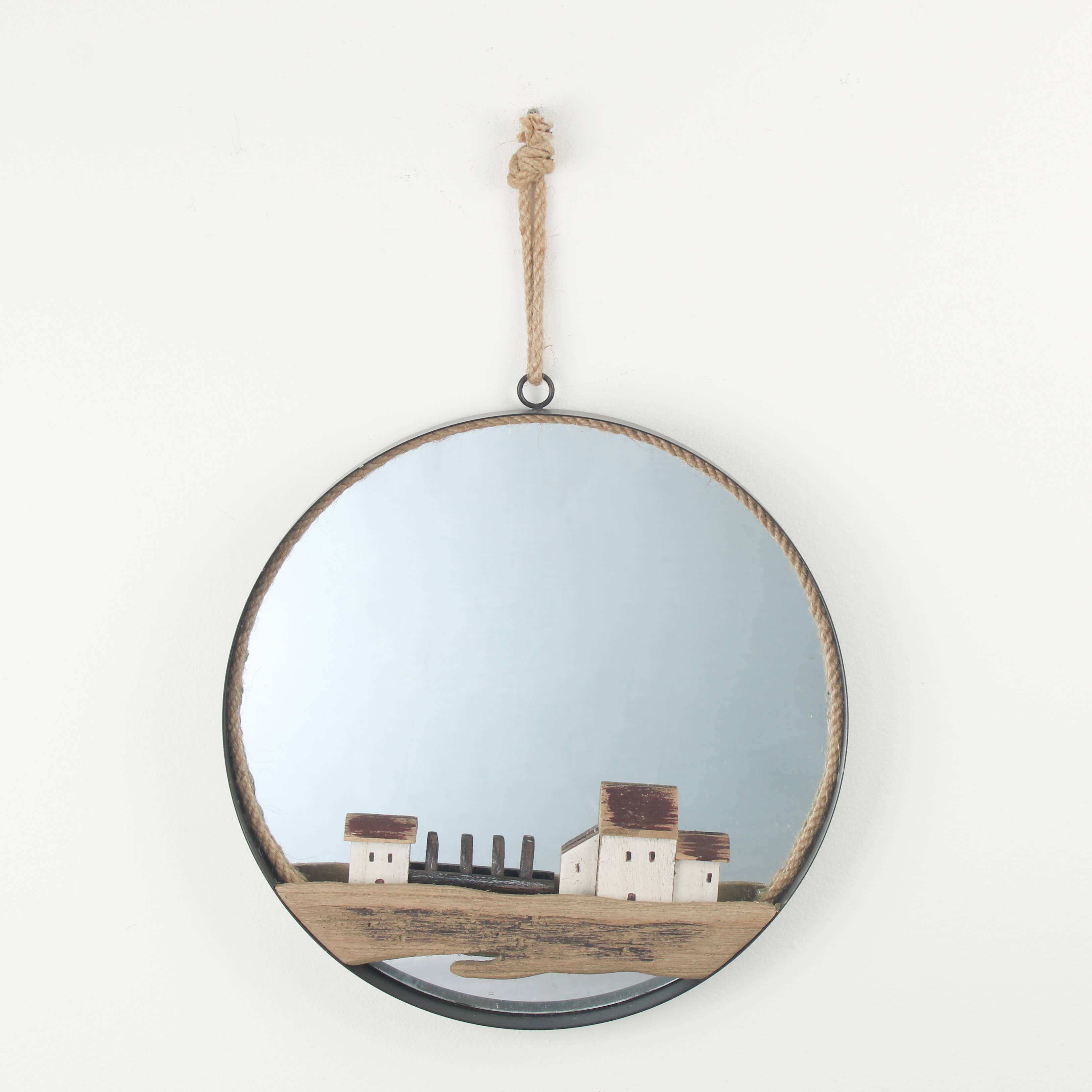 Round mirror with a decorative frame hanging on a white wall, reflecting a scenic view.